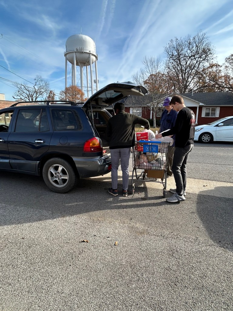 Volunteers loading pantry bags into car.